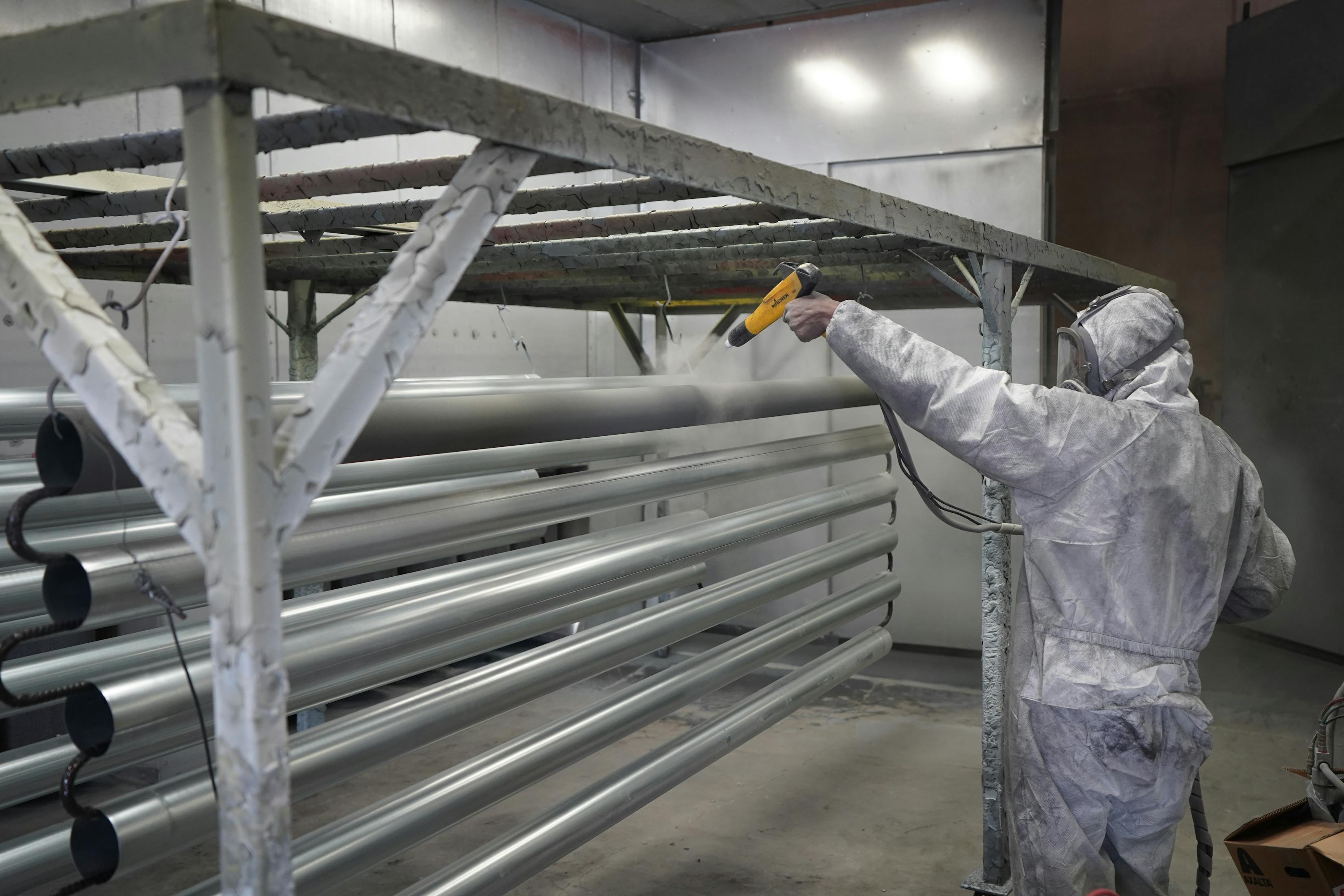 Application de revêtement industriel sur pièces d'acier en cabine de peinture